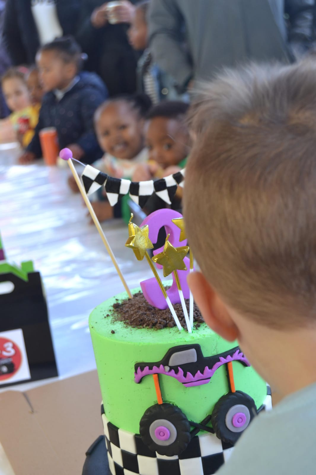 Child looking at a monster-truck birthday cake