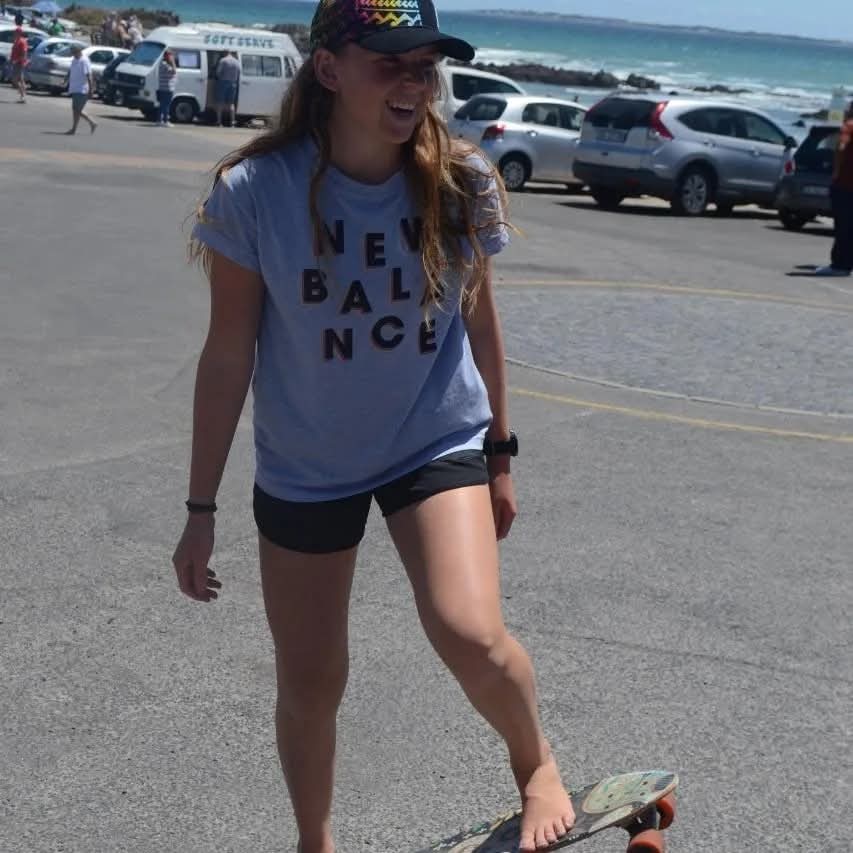 Young woman standing with a skateboard in a car park