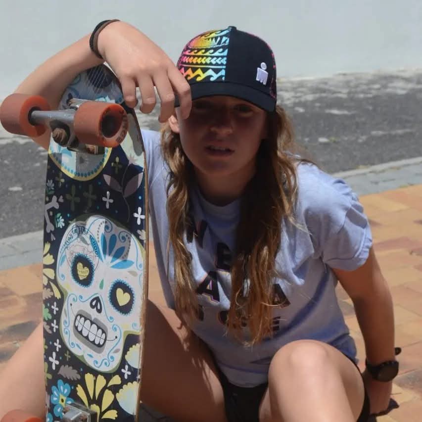 Young woman seated against a wall with a skateboard